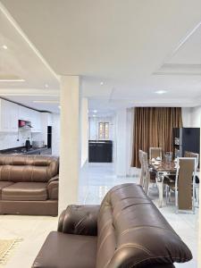 a living room with a leather couch and a dining room at newtown apartment olaleye iporin surulere nigeria in Iponri