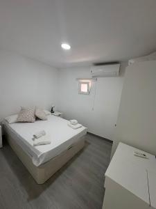a white bedroom with a bed and a window at Monte Victoria Vibes 2 rooms in Málaga