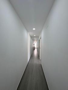 an empty hallway with white walls and a wooden floor at Monte Victoria Vibes 2 rooms in Málaga