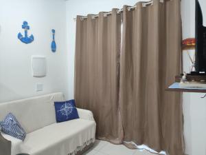 a living room with a couch and a curtain at Residencial Prais Dos Corais H106 in Santa Cruz Cabrália
