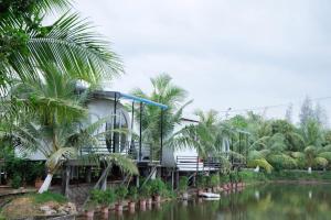 a building with palm trees next to a river at Khu DL ST Cánh Đồng Vàng in Yên Ha