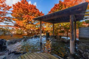 een vijver in een tuin met herfstbladeren bij KAMENOI HOTEL Aomori Makado in Noheji