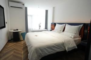 Un dormitorio con una gran cama blanca y una ventana. en Haiman Hotel海曼酒店, en Bangkok