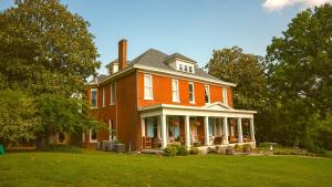 a large red brick house on a grass field at The Magnolia Mansion 6 Minutes to Broadway on 4 Acres in Nashville