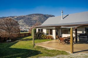 a house with a patio with a table and chairs at Vista Vale - Wanaka Holiday Home in Wanaka