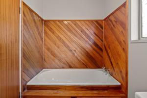 une baignoire avec des boiseries dans une salle de bain dans l'établissement Serenity Lakehouse - Rotorua Holiday Home, à Rotorua 22 autres photos