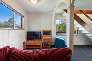 un salon avec un canapé et une télévision dans l'établissement Serenity Lakehouse - Rotorua Holiday Home, à Rotorua