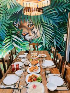 a long table with plates of food and a tiger mural at The Parrot Inn Kanchanaburi in Kanchanaburi +17 photos