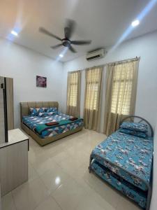 a bedroom with two beds and a ceiling fan at KTL Homestay in Kuantan