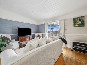 un salon avec un canapé blanc et une télévision dans l'établissement Broughton Cottage, à Katoomba