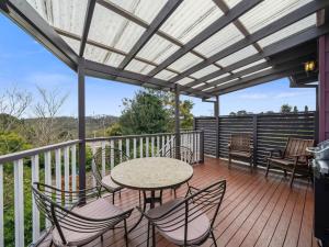 un patio avec une table et des chaises sur une terrasse dans l'établissement Broughton Cottage, à Katoomba
