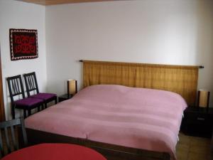 a bedroom with a pink bed and two chairs at Chambre d'hôtes Littoral 65 in Chez-le-Bart