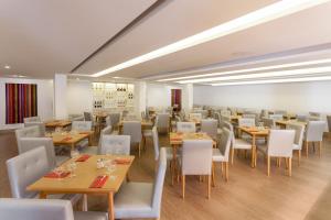 a restaurant with wooden tables and white chairs at Hotel Londres Estoril / Cascais in Estoril