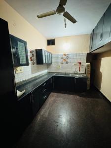 a kitchen with black cabinets and a ceiling fan at LUXE Premium homestay in Mysore