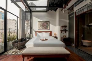 a bedroom with a large bed and a bath tub at Anima Saigon Boutique - Vietnamese Contemporary Art Hotel in Ho Chi Minh City