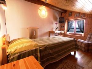 a bedroom with a bed and a couch and a window at Hotel Alpe Fleurie in Champoluc
