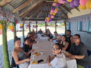 un grupo de personas sentadas en una mesa en la playa en Jaymy Beach Fales, en Lepa