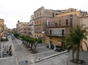 una calle urbana vacía con palmeras y edificios en B&B Notti Sikane, en Porto Empedocle