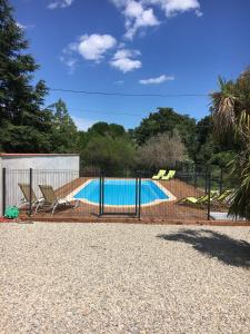 a swimming pool with two chairs and a fence at Les Mimosas Apartments in Villelongue-dels-Monts