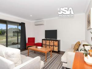 Una sala de estar con muebles blancos y un televisor de pantalla plana. en Cherrywood Cottage - Pet Friendly, en Moonbah