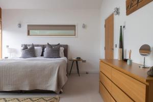 a white bedroom with a bed and a dresser at Mayflower lakeside hot tub in South Cerney +47 photos