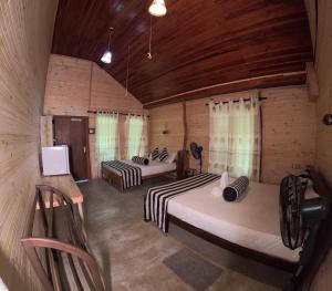 deux lits dans une chambre aux murs en bois dans l'établissement Green Garden Resort, à Habarana 103 autres photos