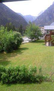 a field of grass with a house and mountains in the background at Appartamento Borgo Rio Muri in Auronzo di Cadore