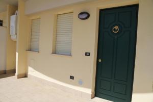 eine grüne Tür in einem Zimmer mit zwei Fenstern in der Unterkunft Appartamenti Il Cerqueto 2 in Terni