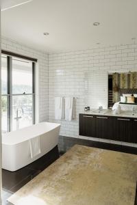 La salle de bains blanche est pourvue d'une baignoire et d'une grande fenêtre. dans l'établissement Potager House, à Carool 10 autres photos