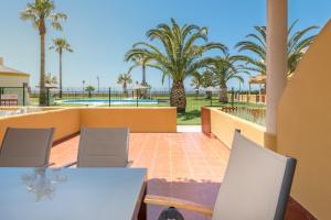 un patio con mesa, sillas y palmeras en Apartamento Lance Playa en Tarifa