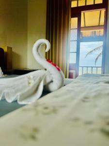 a white snake is sitting on a bed at The Family Beach Villa in Uswetakeiyawa