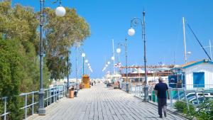 a man walking down a boardwalk near some boats at Finikoudes Marina View #201 in Larnaka