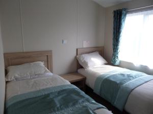 two beds in a small room with a window at Clearwater lodge in Perranporth