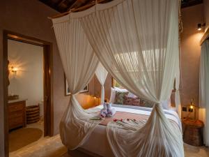 a bedroom with a canopy bed with a teddy bear on it at Tebola Villa Resort in Sidemen