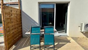 two blue chairs sitting on a table in front of a house at Lits faits, valise à poser, 3 mn Futuroscope in Chasseneuil-du-Poitou