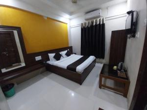 舍地Hotel Sachidanand-Walkable distance from Temple的房间里有一张床和一张桌子的卧室