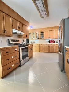 a large kitchen with wooden cabinets and stainless steel appliances at Spacious Getaway Two Homes on a Tranquil Vineyard Ideal for Large Groups in Keremeos +43 photos