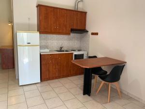 a kitchen with a wooden table and a white refrigerator at Hotel Aki in Loutra Edipsou
