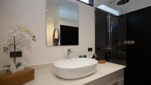 un bagno bianco con lavandino e doccia di Villa Thansamaay by Elite Havens a Laem Sor Altre 28 foto
