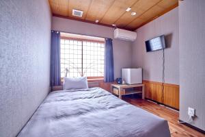 a bedroom with a bed and a tv and a window at ホテル海里 in Fujikawaguchiko