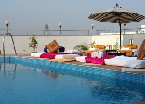 una fila di letti posti accanto alla piscina di The Oasis a Vadodara