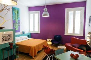 a bedroom with purple walls and a bed and a couch at Il Fonticolo Room & Breakfast in Modena