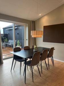 a dining room with a black table and chairs at Topmoderne og bynær villa in Holstebro