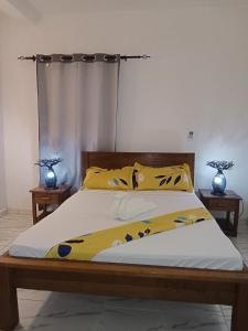 ein Schlafzimmer mit einem Bett mit gelben und blauen Kissen in der Unterkunft Summer Dreams in Nosy Be
