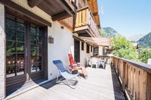a deck with chairs and tables on a building at Chalet Le Tougne in Champagny-en-Vanoise