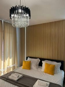 una camera da letto con un letto con cuscini gialli e un lampadario a braccio di Sandanski Apartments Park Center a Sandanski