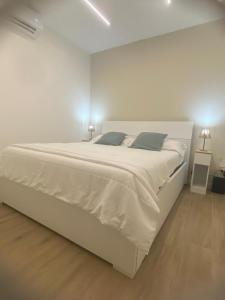 a white bedroom with a large white bed with two lamps at AmaRé House in Bari