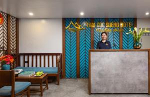 a woman standing behind a podium in a room with a mural at Tam Coc Sueno Hotel in Ninh Binh