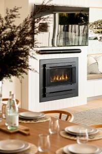 a fireplace in a living room with a table with plates at Luxury Pool Sauna Spa Tennis Court in Mount Martha