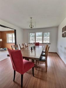 a dining room with a wooden table and red chairs at Vineyard Home Casa De Herrera in Keremeos